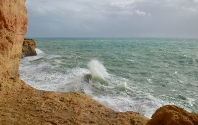 Scenic view of shore and sea against cloudy sky