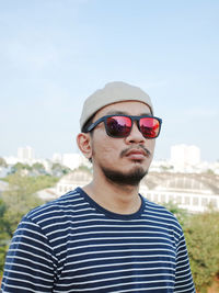 Portrait of young man wearing sunglasses against sky