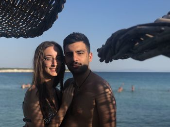 Portrait of young couple in sea against sky