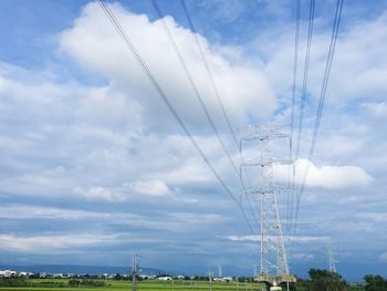 Low angle view of electricity pylon against cloudy sky