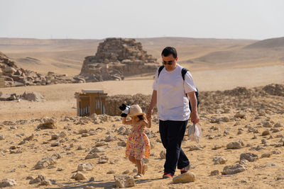 Father with daughter walking in front of the pyramid of mikerin on the giza plateau