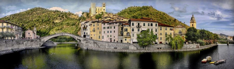 Bridge over river by buildings against sky in city