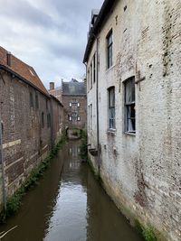 Canal amidst old buildings against sky