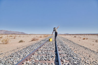 Rear view of man standing on railroad track