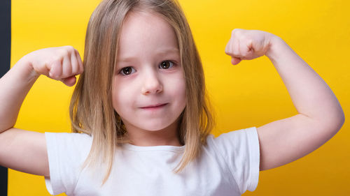 Portrait of young woman against yellow background