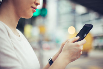 Midsection of woman using phone while standing in city