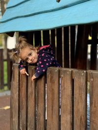 Portrait of cute girl standing by fence