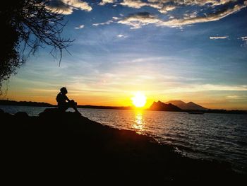 Silhouette of people in sea at sunset