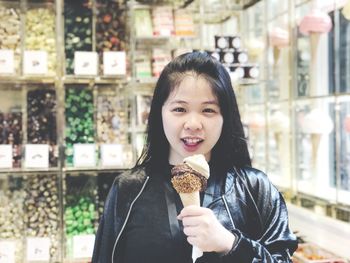 Portrait of young woman having ice cream cone in store