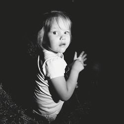 Cute girl smiling while standing against black background