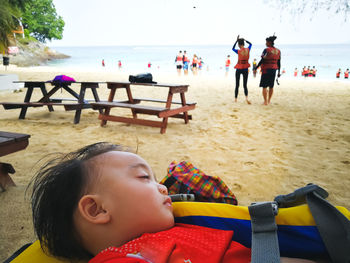 Close-up of girl sleeping at beach against sky