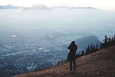 Rear view of man looking at city in foggy weather