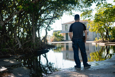 Rear view of man standing on footpath by lake