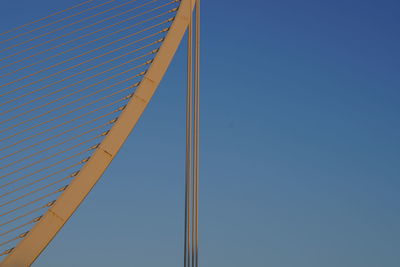 Low angle view of rollercoaster against clear blue sky