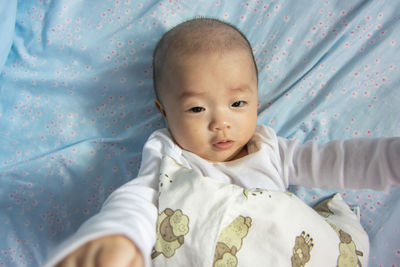 Portrait of cute baby lying on bed