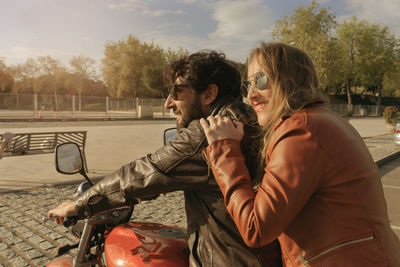 Couple riding motorcycle on road against sky