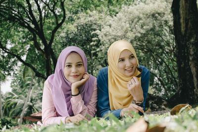 Portrait of smiling woman with friend lying on field