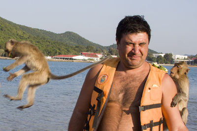 Man wearing life jacket amidst monkeys at beach