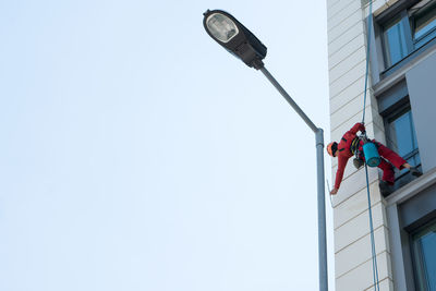 Low angle view of window washer on building