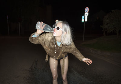 Young woman drinking water from sunglasses