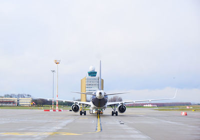 Airplane on airport runway against sky