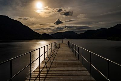 Pier over lake against sky during sunset