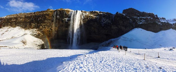 Panoramic view of people on snowcapped mountain against sky