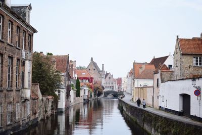 Canal amidst buildings against clear sky