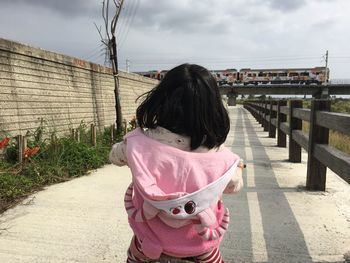 Rear view of woman with umbrella against sky