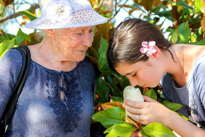 Young woman smelling white magnolia by grandmother