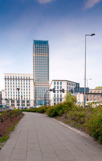 Road by buildings against sky in city