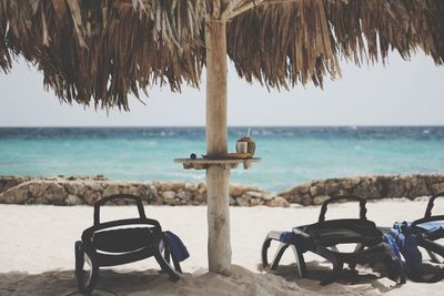 Chairs on beach by sea against sky