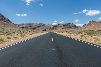 Empty road amidst mountains against sky