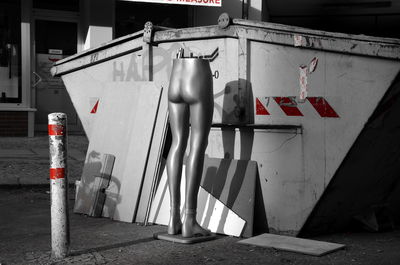 Mannequin by container on footpath