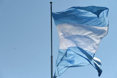 Low angle view of flags against clear blue sky