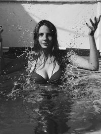 Portrait of young woman splashing water in wading pool