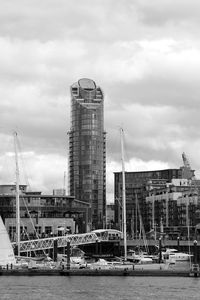 Cranes at harbor against sky in city