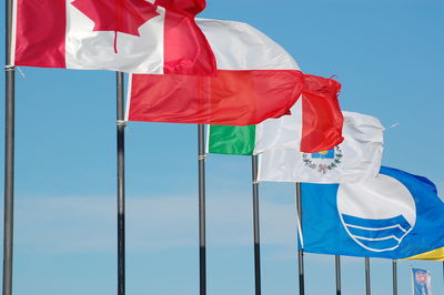 Low angle view of flags against blue sky