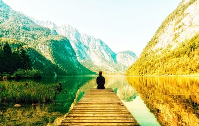 Rear view of man looking at lake against mountain