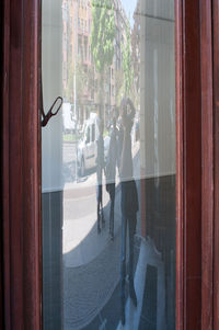 Reflection of man photographing on window