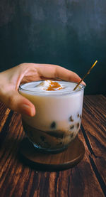 Cropped hand of woman holding drink on table