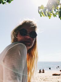 Portrait of man wearing sunglasses at beach against sky