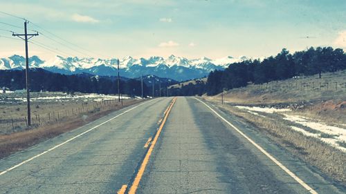 Road by mountain against sky during winter