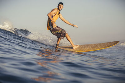 Side view of man surfing on sea against sky