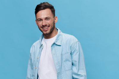 Portrait of young man standing against blue background