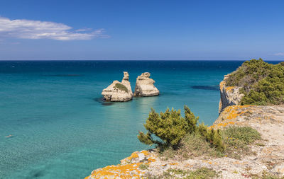 Scenic view of rocks in sea against blue sky