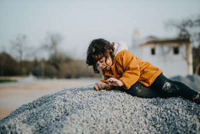 Rear view of boy on rock against sky during winter