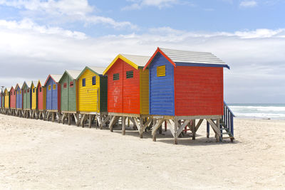 Hooded chairs on beach against cloudy sky