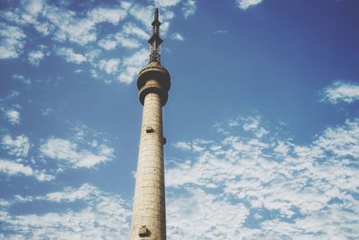 Low angle view of communications tower against cloudy sky