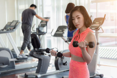 Portrait of young woman lifting dumbbells in gym